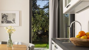A modern kitchen with a dining area, a vase with flowers, and a window with a view of greenery. - Dèpendance - Lequile - Alfa Country House (Lequile)
