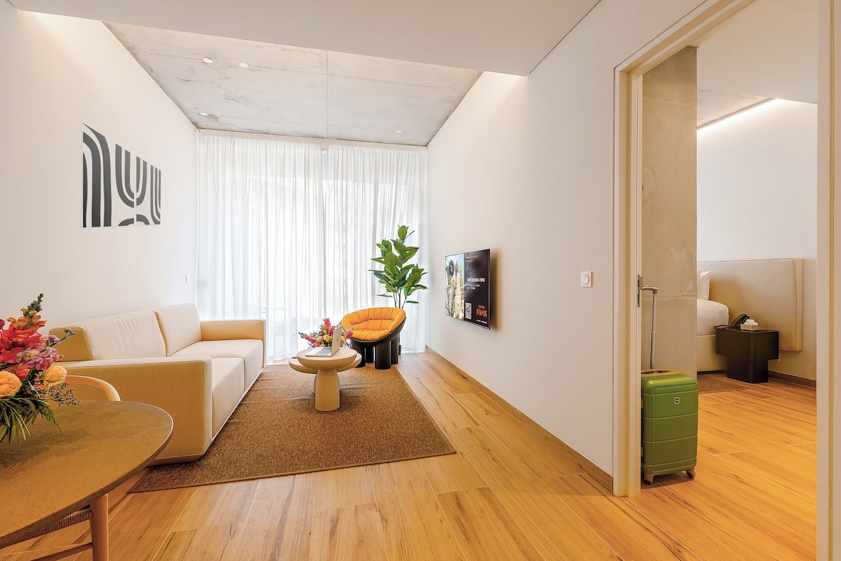 Un salon moderne avec un canapé, une table basse et une valise verte.