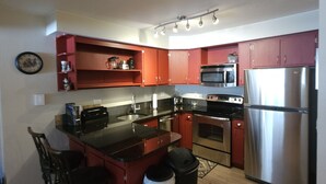 Una cocina compacta con una isla central, electrodomésticos de acero inoxidable y armarios de madera.
