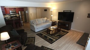 Un espacio habitable compacto con kitchenette, un sofá, una mesa de centro y un televisor.