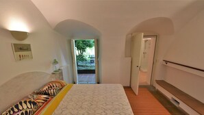 A bedroom with a bed, a bench, a door, and a view of the outdoors. - Beautiful private villa for 6 guests with WIFI, A/C, TV, patio and pets allowed (Cosio Valtellino)