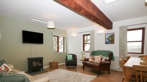 A living room with a fireplace, sofas, a dining table, and a TV. - Winder Green (Penrith)