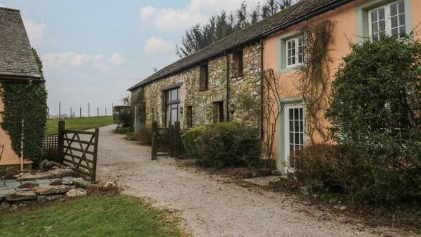 A rural property with stone buildings, a gravel driveway, and surrounding greenery. - Winder Green (Penrith)