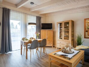Una sala de estar moderna con comedor, muebles de madera y televisor.