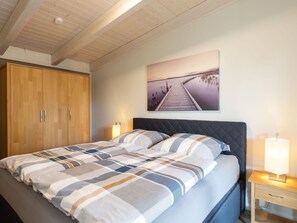 Un dormitorio con cama, armario de madera y un cuadro de un muelle.