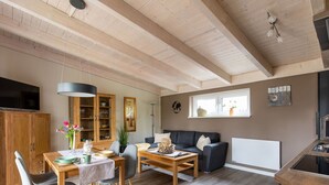 A spacious living area with a dining table, chairs, a sofa, and a kitchen area. - Cosy apartment for 2 people with WIFI, TV and terrace (Osten)