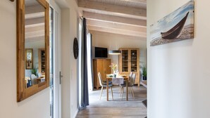 A modern interior with a dining area, wooden beams on the ceiling, and a large mirror on the wall. - Cosy apartment for 2 people with WIFI, TV and terrace (Osten)