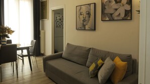 A living room with a grey sofa, a dining table with chairs, and two wall-mounted artworks. - Beautiful apartment for 4 guests with WIFI, A/C, TV and balcony (Bologna)