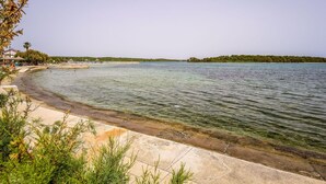 A coastal area with a clear view of the sea, a sandy beach, and a small pier. - Beautiful apartment for 6 guests with private pool, A/C, WIFI, TV, patio and pets allowed (Zadar)