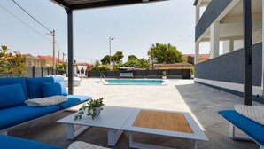 An outdoor seating area with blue sofas and a white coffee table, a pool in the background, and a covered patio. - Beautiful apartment for 6 guests with private pool, A/C, WIFI, TV, patio and pets allowed (Zadar)