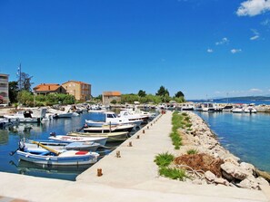 Stunning marina with boats docked along a concrete quay, adjacent to a charming building with a red-tiled roof.