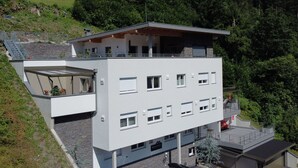 A modern multi-story building with a flat roof, large windows, and a balcony.