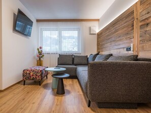 Un salon moderne avec un canapé, un pouf et une table basse.