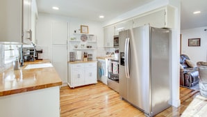 A modern kitchen with white cabinets, a stainless steel refrigerator, and wooden flooring. - Charming Arlington Home w/ Hot Tub & Fenced Yard! (Arlington)