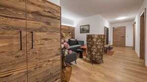 Un salon moderne avec une armoire en bois, un canapé, un fauteuil à motifs floraux et un vase rempli de fleurs.