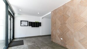 A hallway with a patterned wall, a bulletin board, and a door with a glass panel. - Maria (Bucharest)