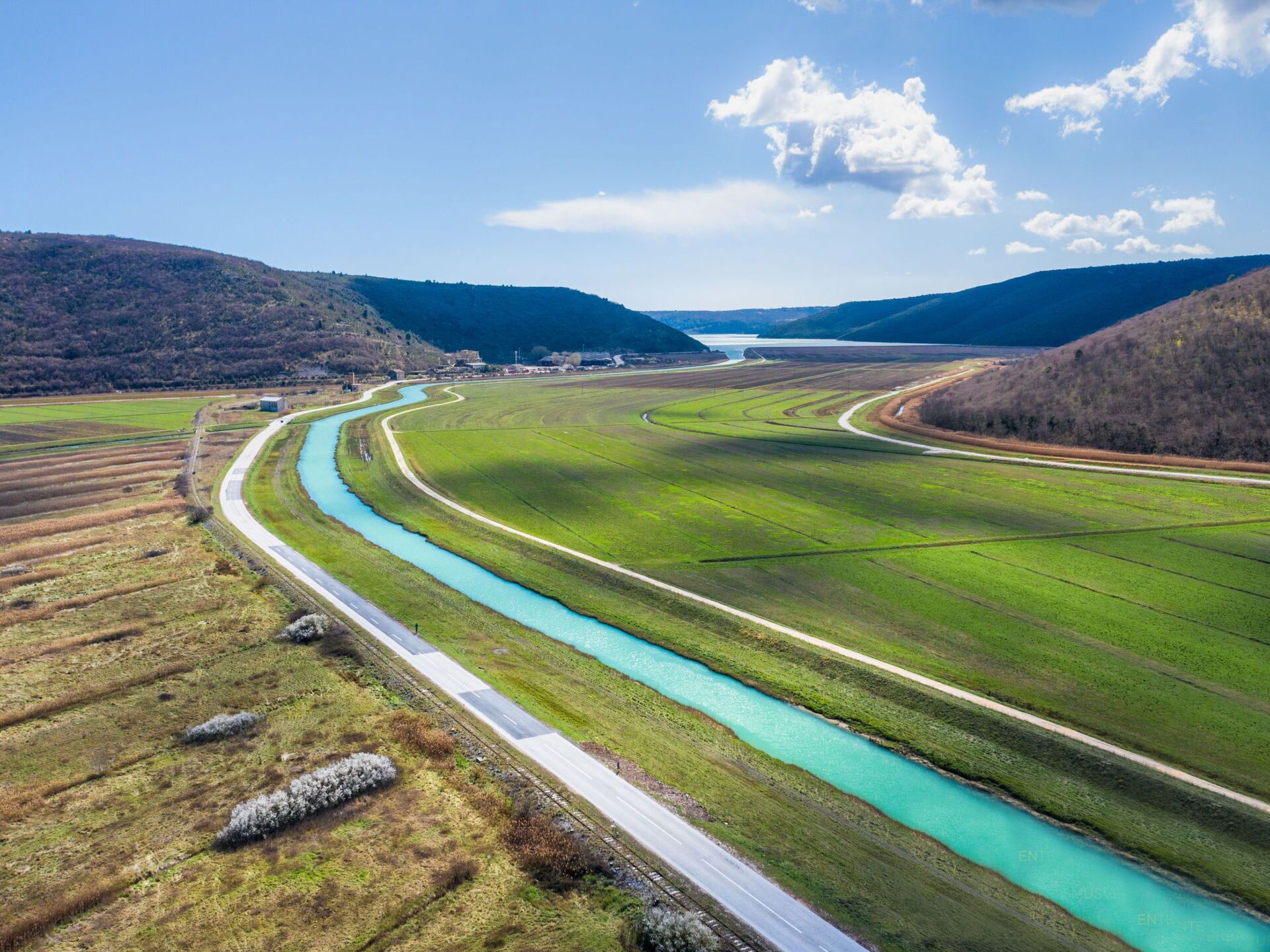 A river winding through a green landscape with a road alongside it.
