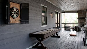 A wooden deck with a dartboard, a bench, and a barbecue grill. - Located on Bear Lake in Tuckasegee, NC.  A scenic getaway for your family event! (Tuckasegee)