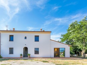 A two-story building with a flat roof, a central entrance, and a small patio area. - Stunning private villa for 4 guests with WIFI, A/C, terrace and panoramic view (Gavorrano)