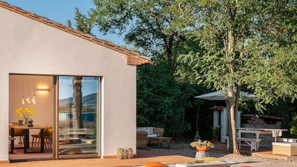 Une maison moderne dotée d’un patio aménagé avec un espace salon extérieur et une table à manger.