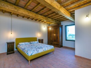 A bedroom with a bed, wooden wardrobe, and a window with a view. - Stunning private villa for 4 guests with WIFI, A/C, terrace and panoramic view (Gavorrano)