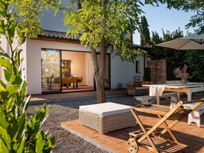A modern outdoor patio with a dining area, a wicker sofa, and a table with a cushion. - Stunning private villa for 4 guests with WIFI, A/C, terrace and panoramic view (Gavorrano)
