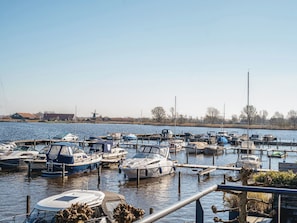 Een jachthaven met verschillende boten afgemeerd, een heldere lucht en een windmolen op de achtergrond.