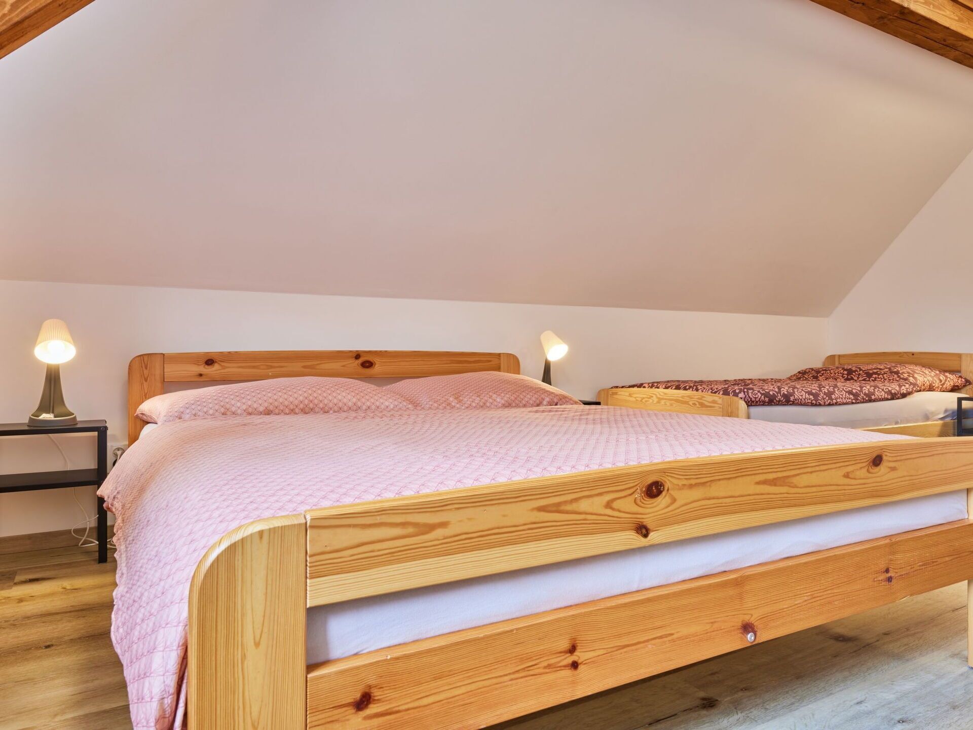 A cozy attic bedroom with a wooden bed and two bedside lamps.