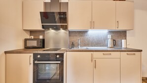 Una cocina moderna con horno empotrado, microondas y campana extractora de acero inoxidable.
