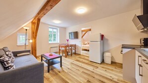 Un loft acogedor con comedor, cocina y entrepiso con cama.