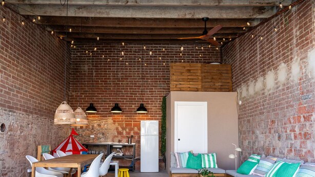 A cozy, rustic room with exposed brick walls, a wooden dining table with chairs, a sofa with cushions, and a ceiling fan. - Wonderful  villa for 7 people with private pool, A/C, WIFI, TV and patio (Malgrat De Mar)