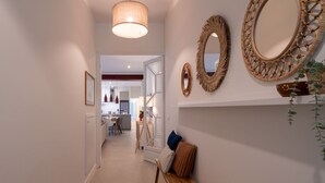 A hallway with a wooden bench, a hanging light fixture, and decorative mirrors on the wall. - Wonderful  villa for 7 people with private pool, A/C, WIFI, TV and patio (Malgrat De Mar)