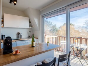 Enjoy a meal on the balcony overlooking the surroundings from the kitchen, which features a coffee maker, wine and glasses.