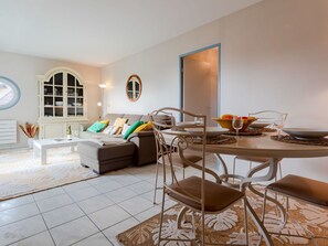 Relax in this stylish living room with a brown sofa, colorful cushions, and a dining table for meals.