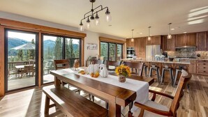 A spacious kitchen with wooden cabinets, a central island, and large windows offering a view of the outdoors.