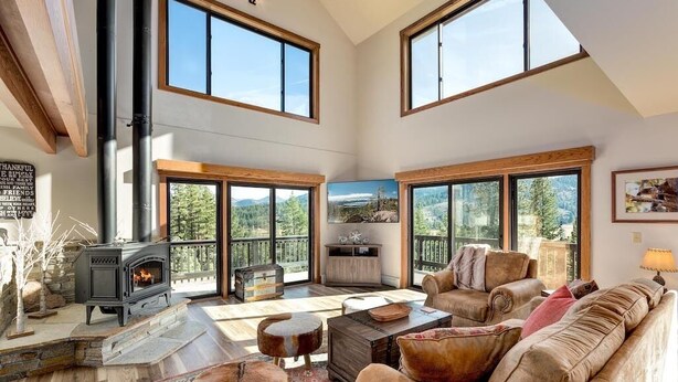 A spacious living room with a fireplace, large windows, and a cozy seating area.