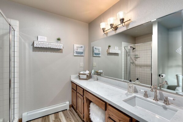 Une salle de bain moderne avec un grand miroir, un meuble-lavabo blanc et un espace douche.