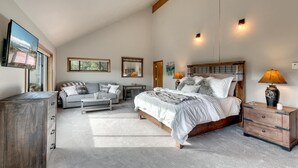 A bedroom with a large bed, a sofa, a desk, and a TV.