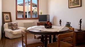 Zona de menjador amb taula rodona, cadires, un televisor i un quadre al mur.