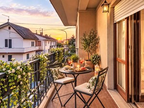 A balcony with a table set for two, surrounded by potted plants and a view of the sunset. - Nice apartment for 5 guests with WIFI, balcony and pets allowed (Ortona)