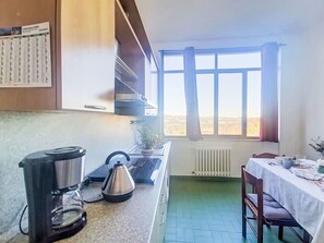 Een keuken met een koffiezetapparaat, waterkoker en een raam met gordijnen.