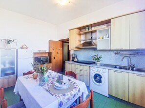 A compact kitchen with a washing machine, a coffee maker, and a dining area with a table set for two. - Nice apartment for 5 guests with WIFI, balcony and pets allowed (Ortona)