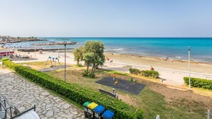 A beach view with a playground, a stone pathway, and a row of trash bins. - Lovely apartment for 6 people with A/C, WIFI, TV and balcony (Rosignano Solvay-castiglioncello)