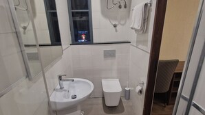 Un baño moderno con lavamanos, inodoro y zona de ducha.