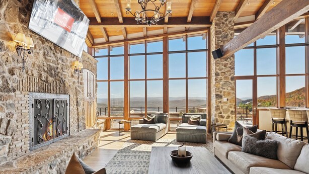 Un salón amplio con paredes de piedra, ventanas grandes y una chimenea.