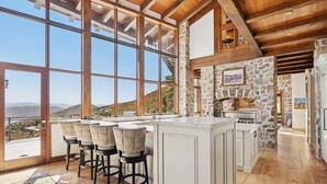 Una cocina con una isla grande, taburetes de bar y vistas a las montañas.