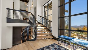 A modern interior with a wooden staircase, large windows, and a bench by the window. - Ski-in/ski-out luxury chalet with hot tub, pool, located in The Colony (Park City)