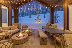 An outdoor seating area with a fire pit, wooden furniture, and a view of a snowy landscape. - Ski-in/ski-out luxury chalet with hot tub, pool, located in The Colony (Park City)