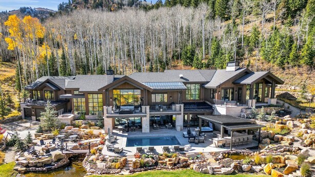 A large, modern house with multiple levels, a swimming pool, and a landscaped garden with a pond. - Ski-in/ski-out luxury chalet with hot tub, pool, located in The Colony (Park City)