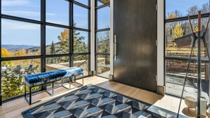 A modern room with large windows, a bench, and a view of the outdoors. - Ski-in/ski-out luxury chalet with hot tub, pool, located in The Colony (Park City)